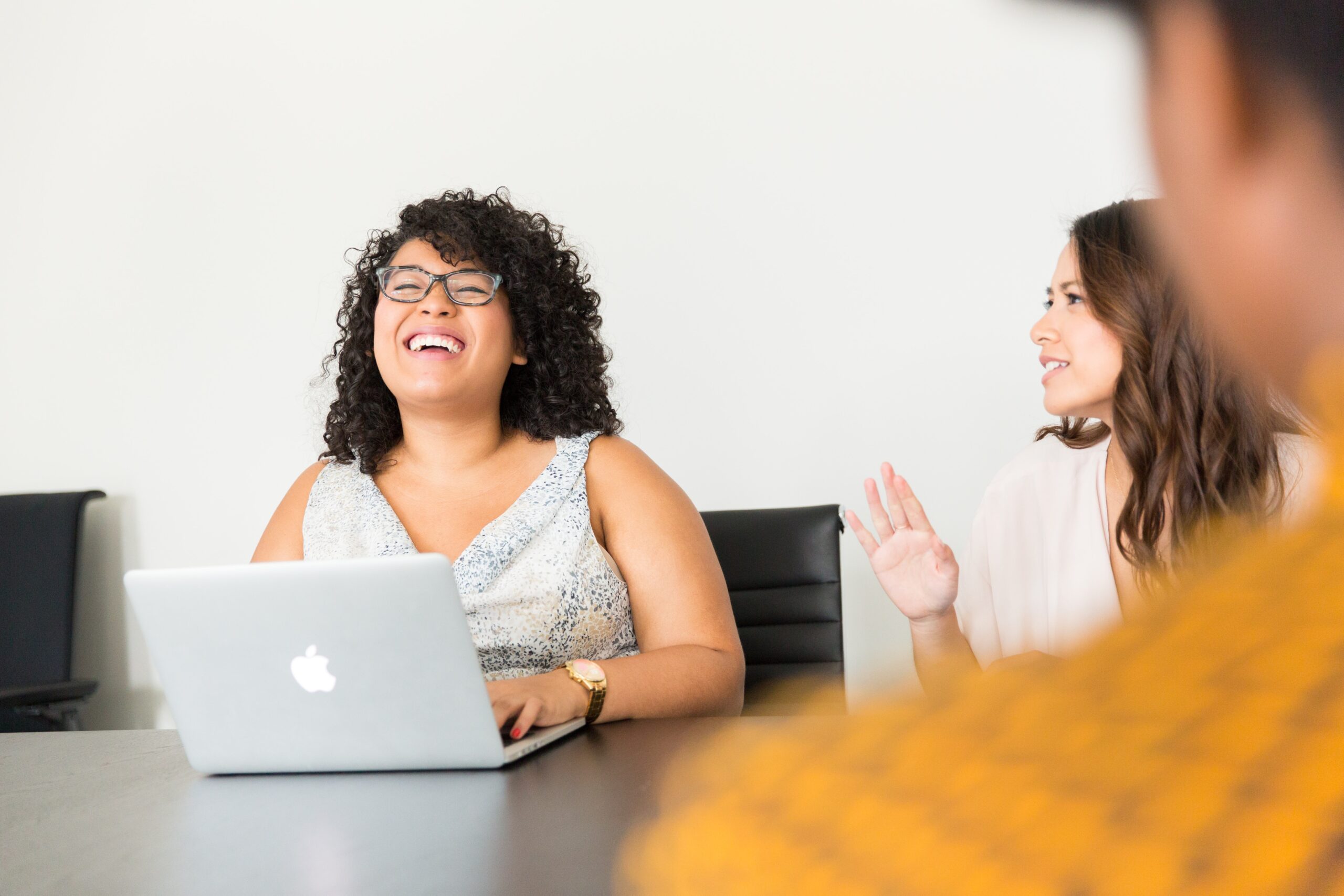 Person on laptop smiling while listening to another person speak